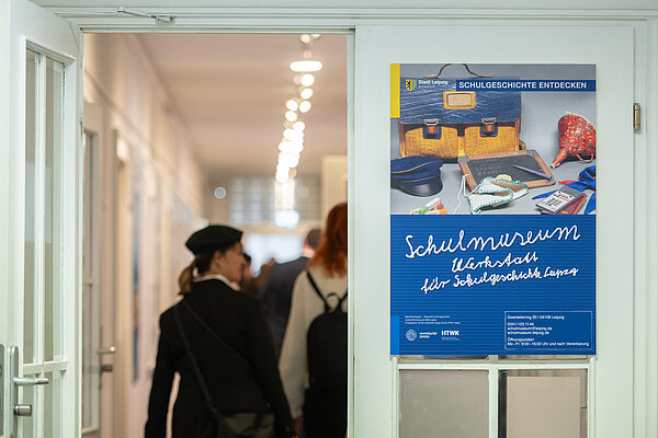 Frau geht durch Tür, daneben ein Plakat