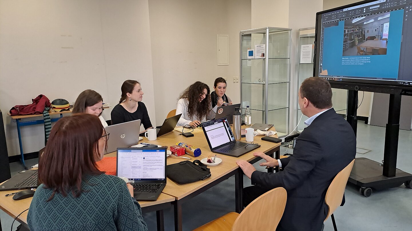 Gruppe Studierender sitzt um einen Tisch, Seminar