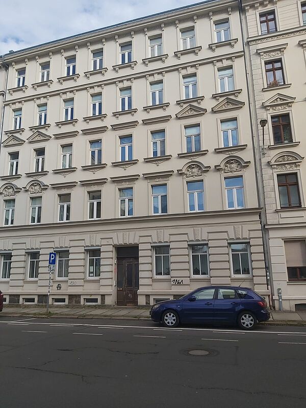 Das Bild zeigt die Fassade eines klassischen, mehrstöckigen Wohn- oder Bürogebäudes, das unter anderen das Institut für Kultur- und Universalgeschichte der Karl-Lamprecht-Gesellschaft e.V. beherbergt. Die Fassade ist in einem eleganten Stil gehalten, typisch für Gründerzeitbauten, mit klaren Linien und symmetrischen Fenstern. Über einigen Fenstern sind dekorative Giebel angebracht, die dem Gebäude zusätzliche architektonische Details verleihen. Das Erdgeschoss hebt sich durch größere Fenster und eine geradlinige Fassadengestaltung ab, die von horizontalen Bändern unterbrochen wird. Die Haustür ist schlicht, weist jedoch typische alte Holzelemente auf, die zu dem klassischen Stil des Gebäudes passen.